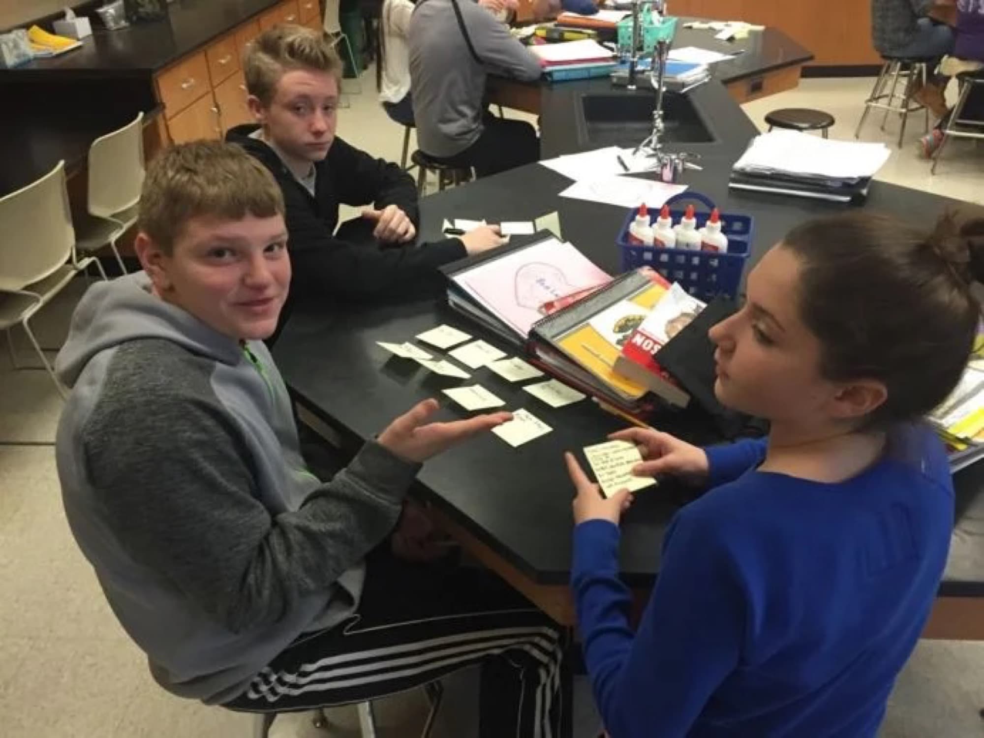 Three students at a lab table comparing post-it notes during brainstorming.